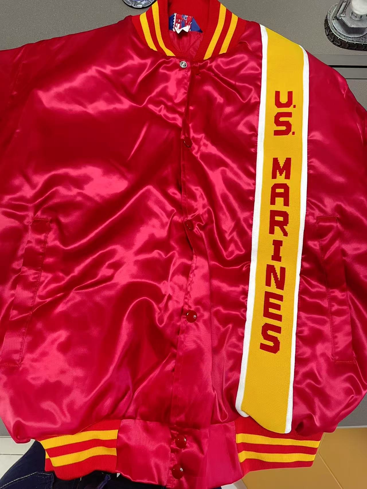 US Marine Corp red varsity style jacket with gold sash stiched in vertically with white stripes either side and US MARINES vertically stitched inside.